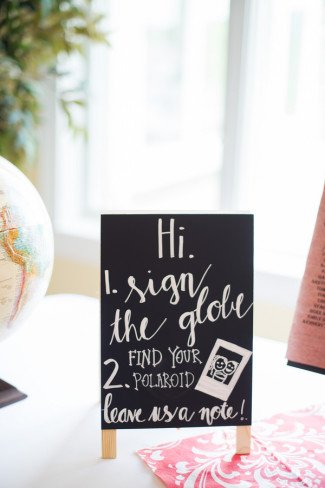Chalkboard sign asking their guests to sign their globe guestbook